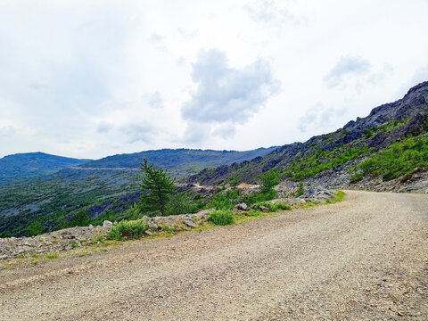 Mountain landscape with a dirt road under a cloudy sky