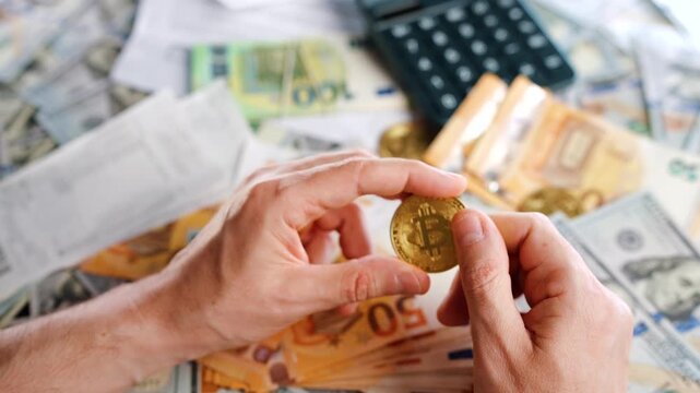 Hands shows silver and golden BTC bitcoin against the dollars and euros