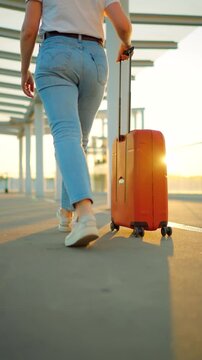 Woman confidently pulling a suitcase in an airport terminal. Back view