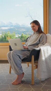 A woman using laptop and enjoying scenic snowy mountain view.