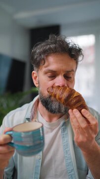 A man enjoying a fresh croissant and coffee for breakfast