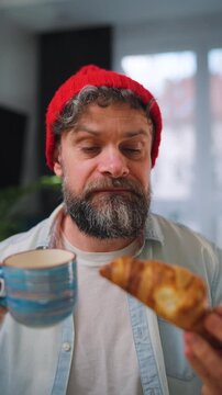 A man enjoying a fresh croissant and coffee for breakfast. Slow motion
