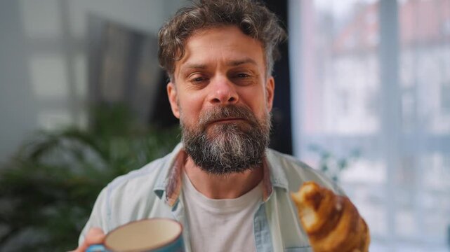A man enjoying a fresh croissant and coffee for breakfast