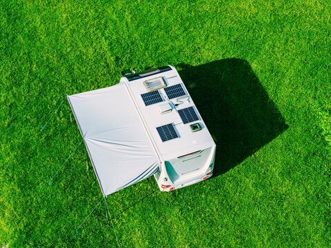 Solar panels mounted on the roof of a camper van parked on a lush green lawn