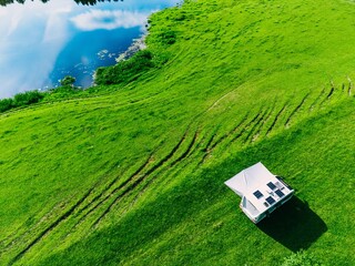 Obraz premium Camper van parked on lush green grass near tranquil water reflecting blue sky