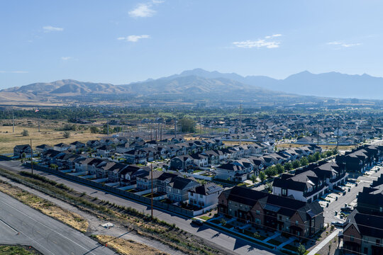 Aerial view of a suburban residential neighborhood with Silicon Slopes and the Wasatch Front hazy from seasonal wildfires as seen from Lehi, Utah, United States.