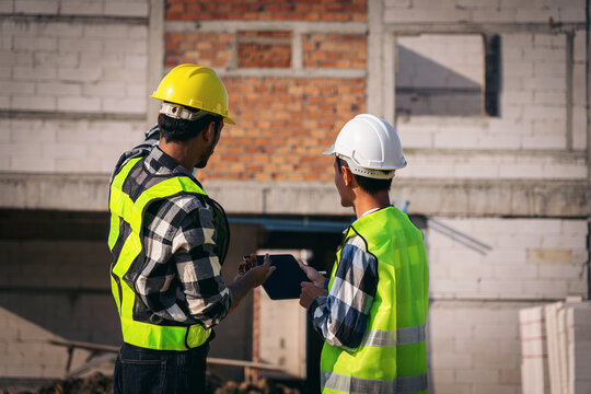 Asian Adult Construction Workers Discussing Plans on a Tablet at