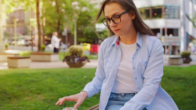 A woman sitting in the park with a laptop and working during the summer day