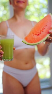 Woman holding a glass of celery juice and a piece of watermelon. Healthy eating