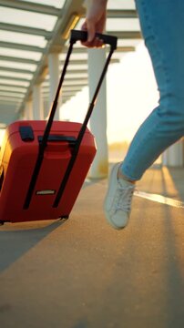 Woman confidently pulling a suitcase in an airport terminal. Slow motion.