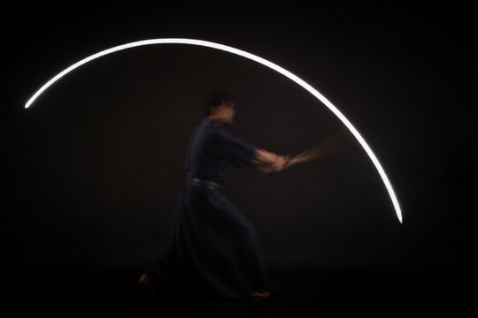 A white arc of light tracing the path of a moving sword.