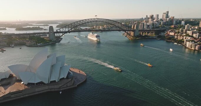 Sydney Harbour cityscape showing the iconic Opera House, Harbour Bridge, and a cruise tourist ship navigating the waters, a travel destination of Australia's famous city landmarks. Aerial view shot