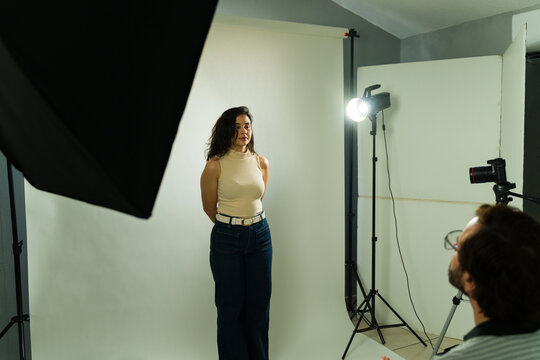 Female talent standing for a casting audition in a photo studio while a producer or director reviews her performance