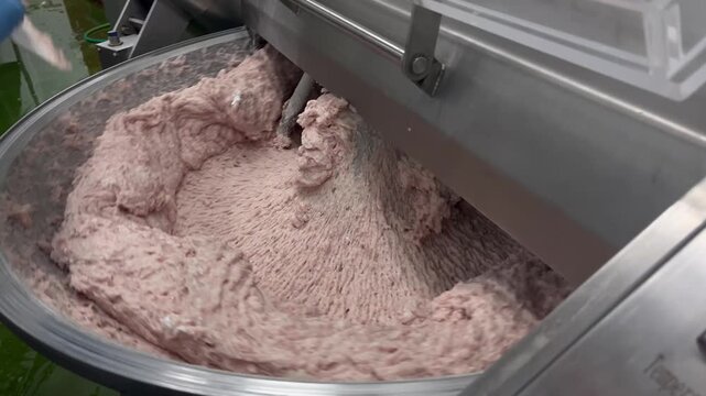 High-capacity bowl cutter mixing meat ingredients in a food manufacturing facility. Industrial chopping and blending process supporting processed meat production, food consistency, and large-scale man