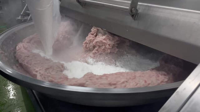 High-capacity bowl cutter mixing meat ingredients in a food manufacturing facility. Industrial chopping and blending process supporting processed meat production, food consistency, and large-scale man