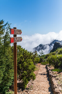 Wooden trail signpost on a scenic stone mountain hiking path above the clouds in Madeira Portugal