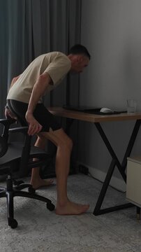 A man working from home sits at his desk, opens his laptop, and begins typing. Concept: freelancing and working from home