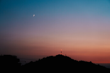 Crescent moon over a mountain silhouette at sunset © Youngkyoung