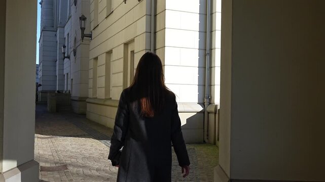 Rear view of a woman walking along a wide historic street between elegant multi-story buildings in Luxembourg