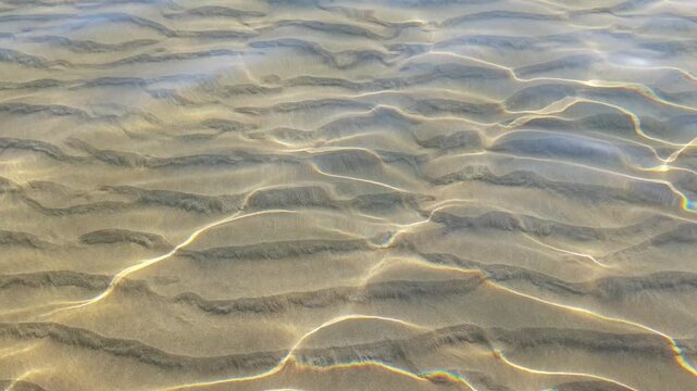 Underwater light patterns on sand, clear water surface with sun reflections, natural abstract background texture, reflection, nature, ocean, sea. 4k video.