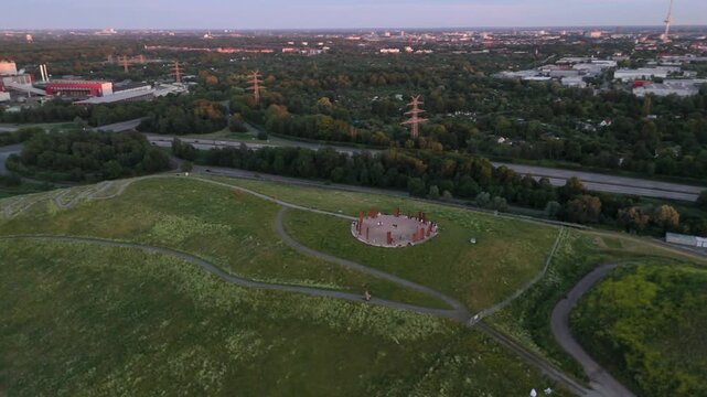 Aerial of Metalhenge, a parkland hill highway and green suburbs at dusk