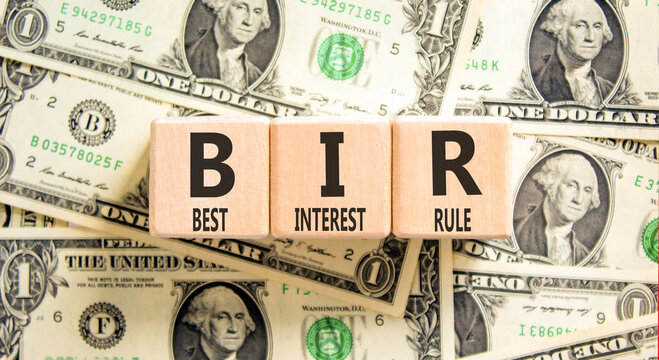 BIR best interest rule symbol. Concept words BIR best interest rule on beautiful wooden blocks. Beautiful dollar bills background. Business BIR best interest rule concept. Copy space.
