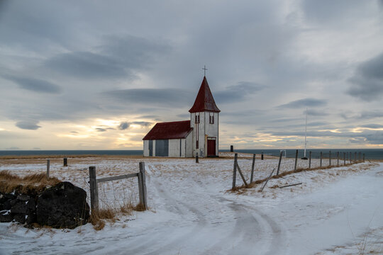 White church with red roof on snowy coastal plain in Iceland