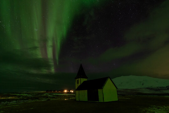Northern lights over small church in snowy Iceland at night