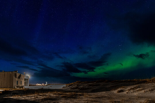 Northern lights over modern cabin in winter landscape, Iceland