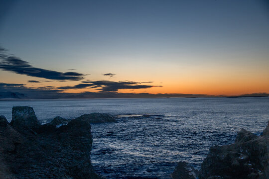Beautiful sunset over the ocean with dark volcanic rocks in the foreground, Arnarstapi, Snaefellsnes, Iceland
