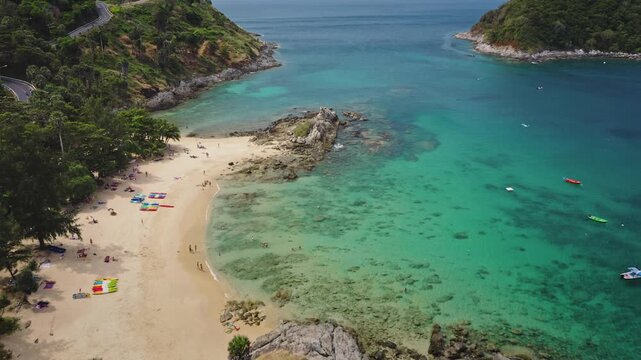 Yanui Beach, Phuket turquoise bay, golden sand, sunbathers and anchored boats along a lush green coastline, perfect tropical vacation and relaxation scene. Travel to Thailand. Aerial view drone flight