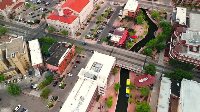 Overhead aerial drone orbits Pueblo Colorado Riverwalk directly above rooftops streets and water canal