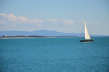 Fototapeta premium serene marine scene with a sailboat sailing in coastal waters