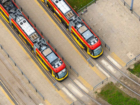 Aerial view of two modern trams running on parallel tracks, representing sustainable transport in Warsaw, Masovian Voivodeship, Poland.