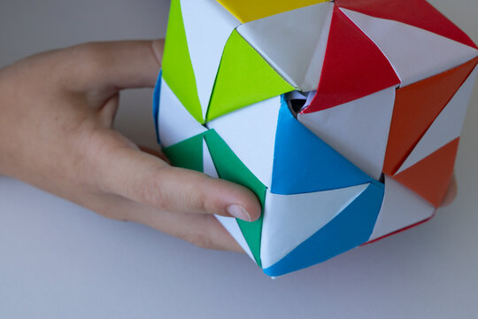 Child playing with colorful origami paper cube toy