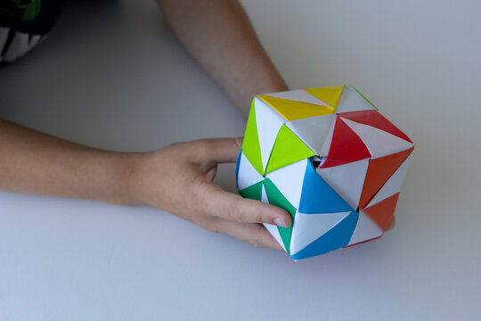 Child playing with colorful origami paper cube toy