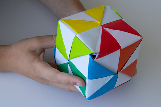 Child playing with colorful origami paper cube toy