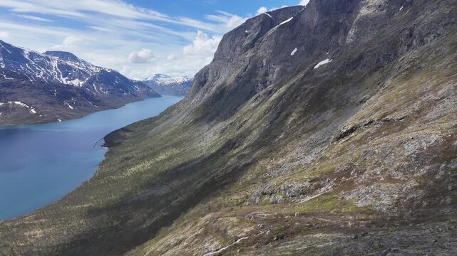 Aerial drone flyover of mountain cliffs adjacent to Lake Gjende at Jotunheimen National Park, Norway