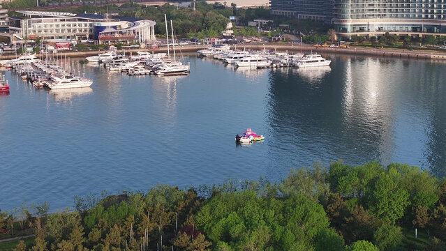 Rizhao harbor bay with yachts docked at marina surrounded by green trees and modern buildings