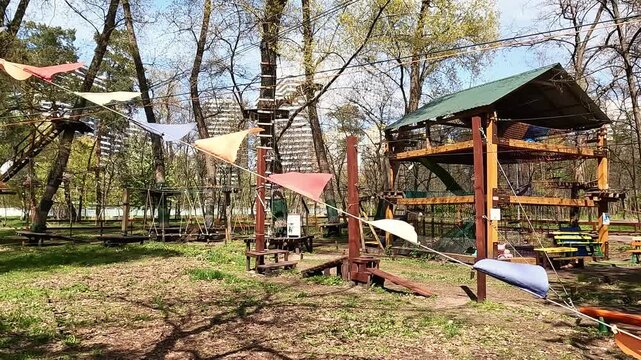 Empty rope park obstacle course with flags hanging in spring forest