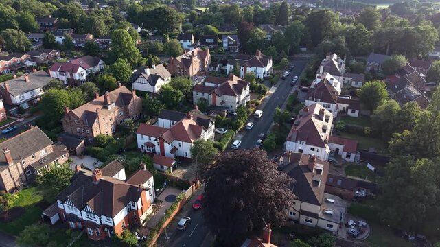 Aerial drone 4K scene showing suburban streets illuminated by warm golden hour sunlight England