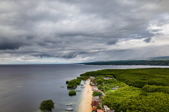 Aerial view of Nusa Lembongan beach and lush green forest under stormy sky