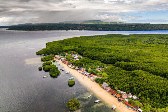 Drone shot showing tropical coastline with dense green mangroves and boats