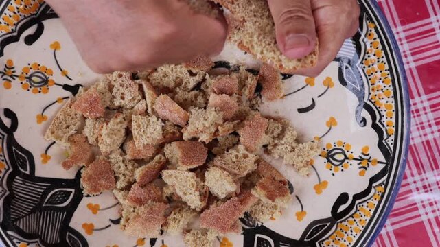 Man tearing bread to prepare traditional Moroccan trid dish