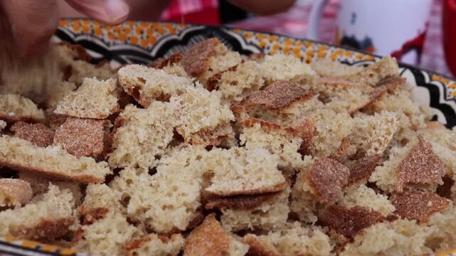Man tearing bread to prepare traditional Moroccan trid dish