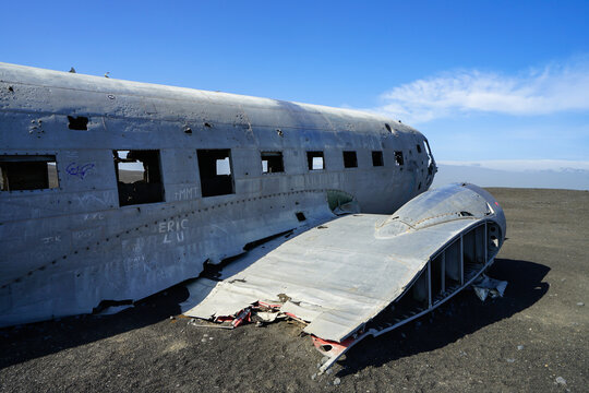 Abandoned aircraft fuselage and tail section lying on a barren landscape under clear blue sky,Solheimasandur Plane Wreck,Iceland