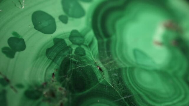 Malachite stone texture, extreme close up. Macro video of polished green stone with typical band patterns. Moving textures on black background