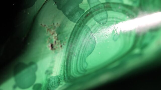 Malachite stone texture, extreme close up. Macro video of polished green stone with typical band patterns. Moving textures on black background