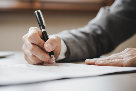 Extreme close up of businessman signing official document with black pen.
