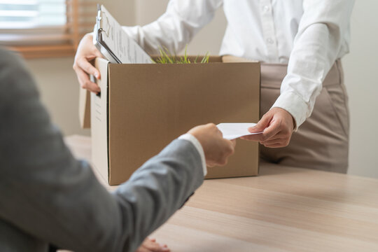 Close up of employee handing resignation letter to manager with cardboard box.